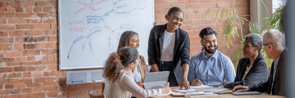 Advisor guiding a diverse team through documents and tablets during a collaborative planning and decision-making session.